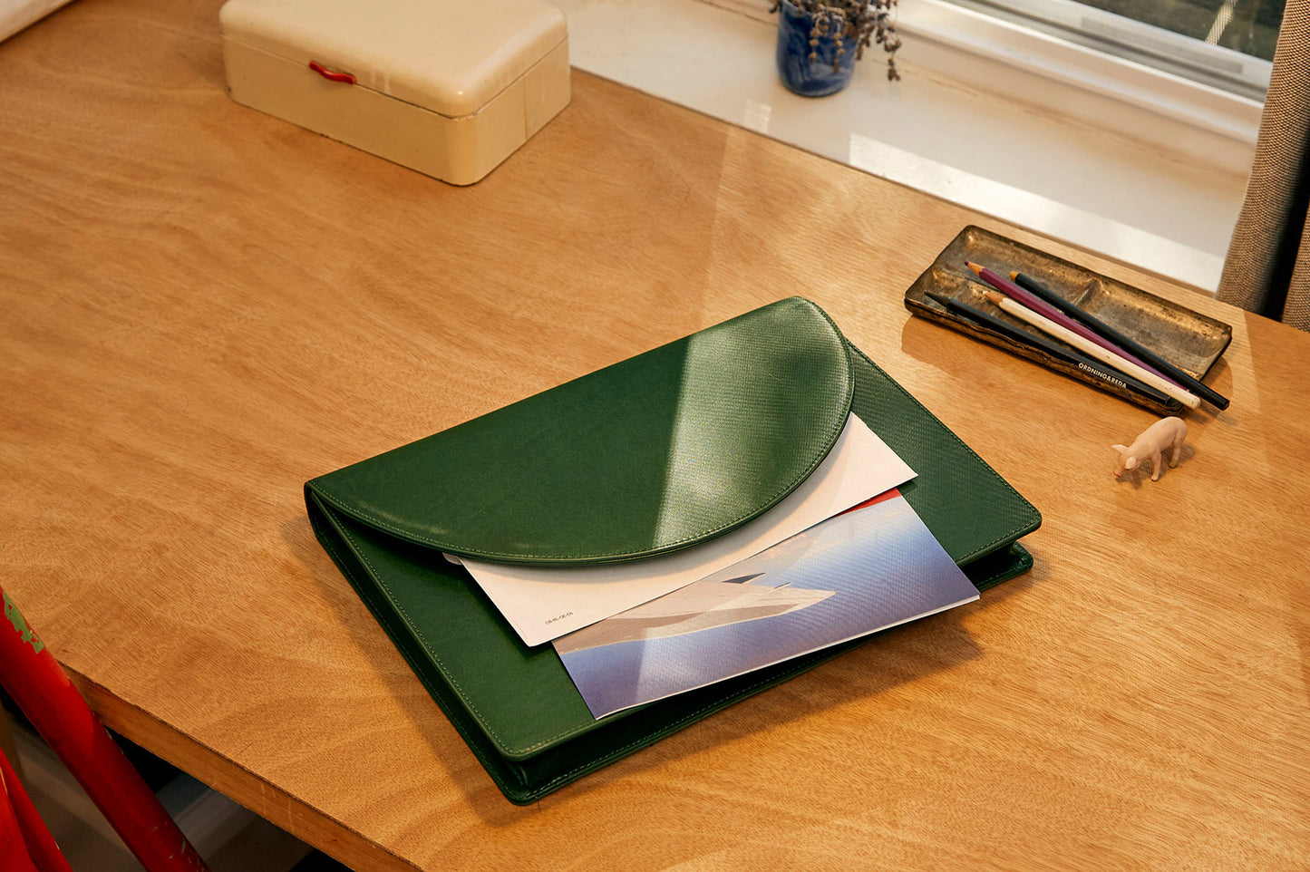 Leather green document folio on table with papers inside