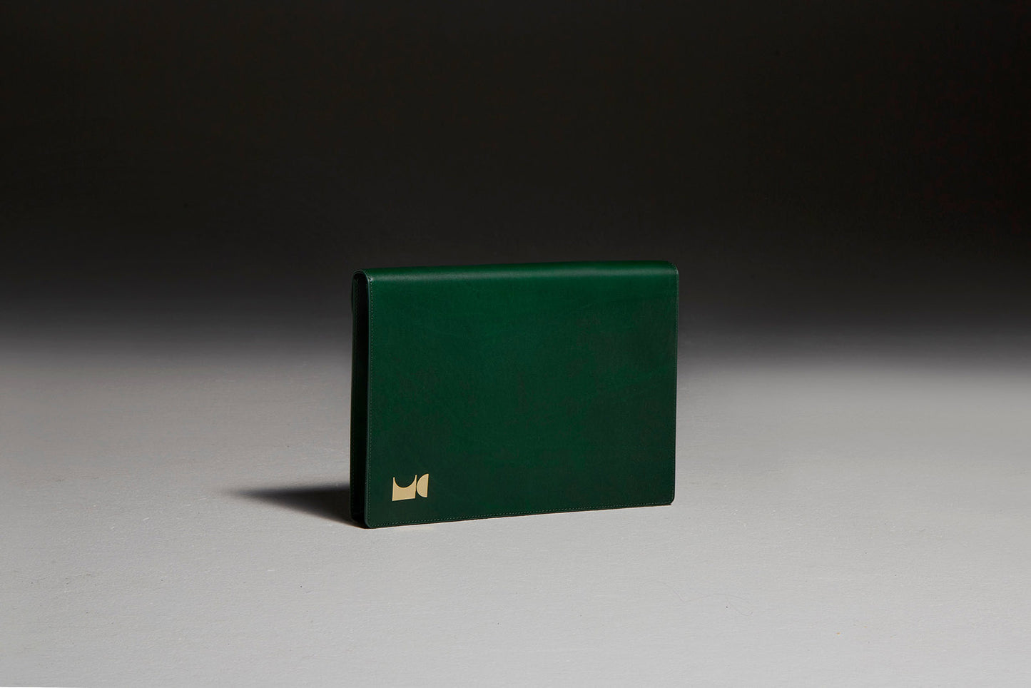 Green leather document folio sitting in front of black backdrop