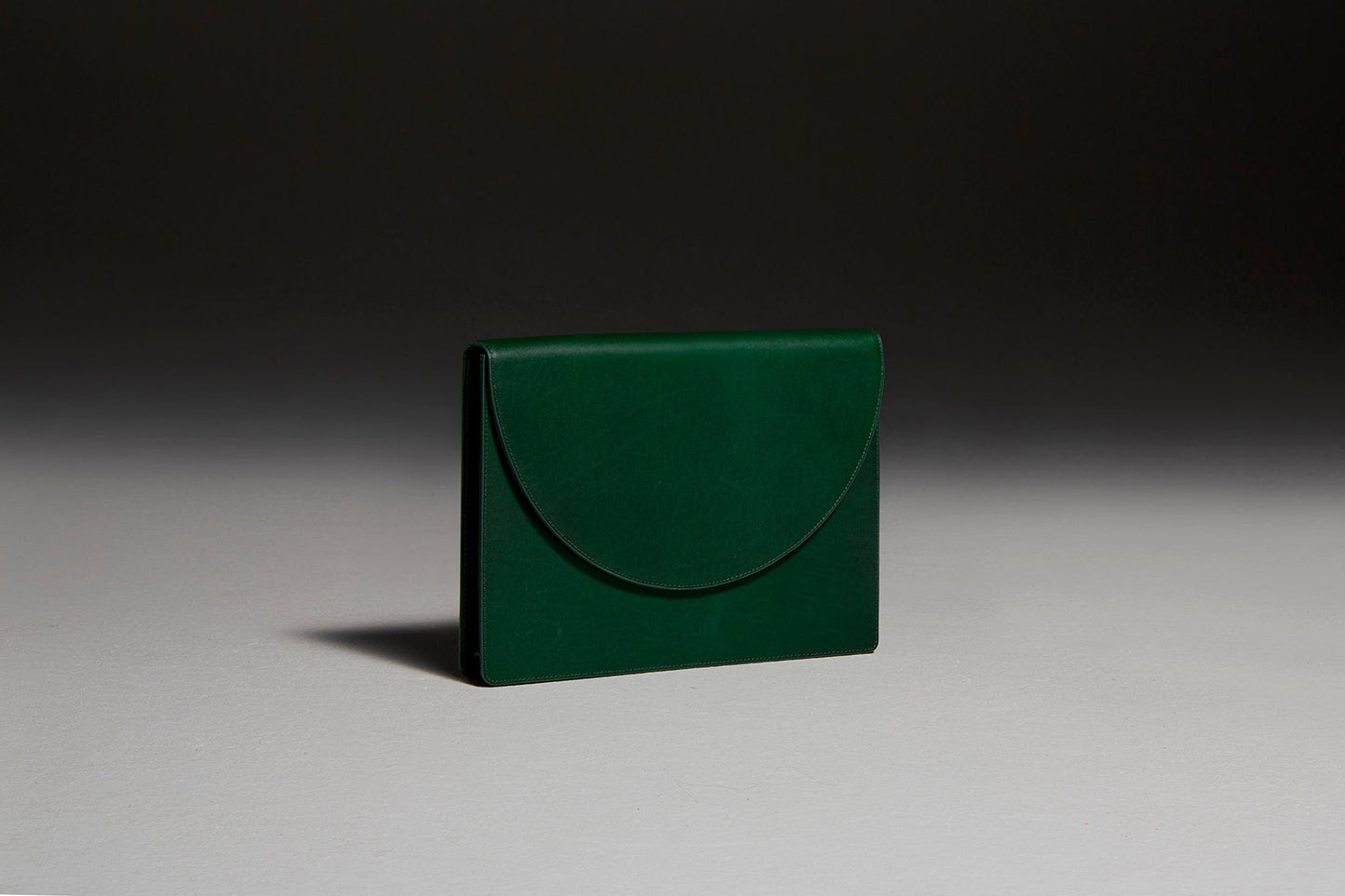 Green leather document folio sitting backwards in front of black backdrop