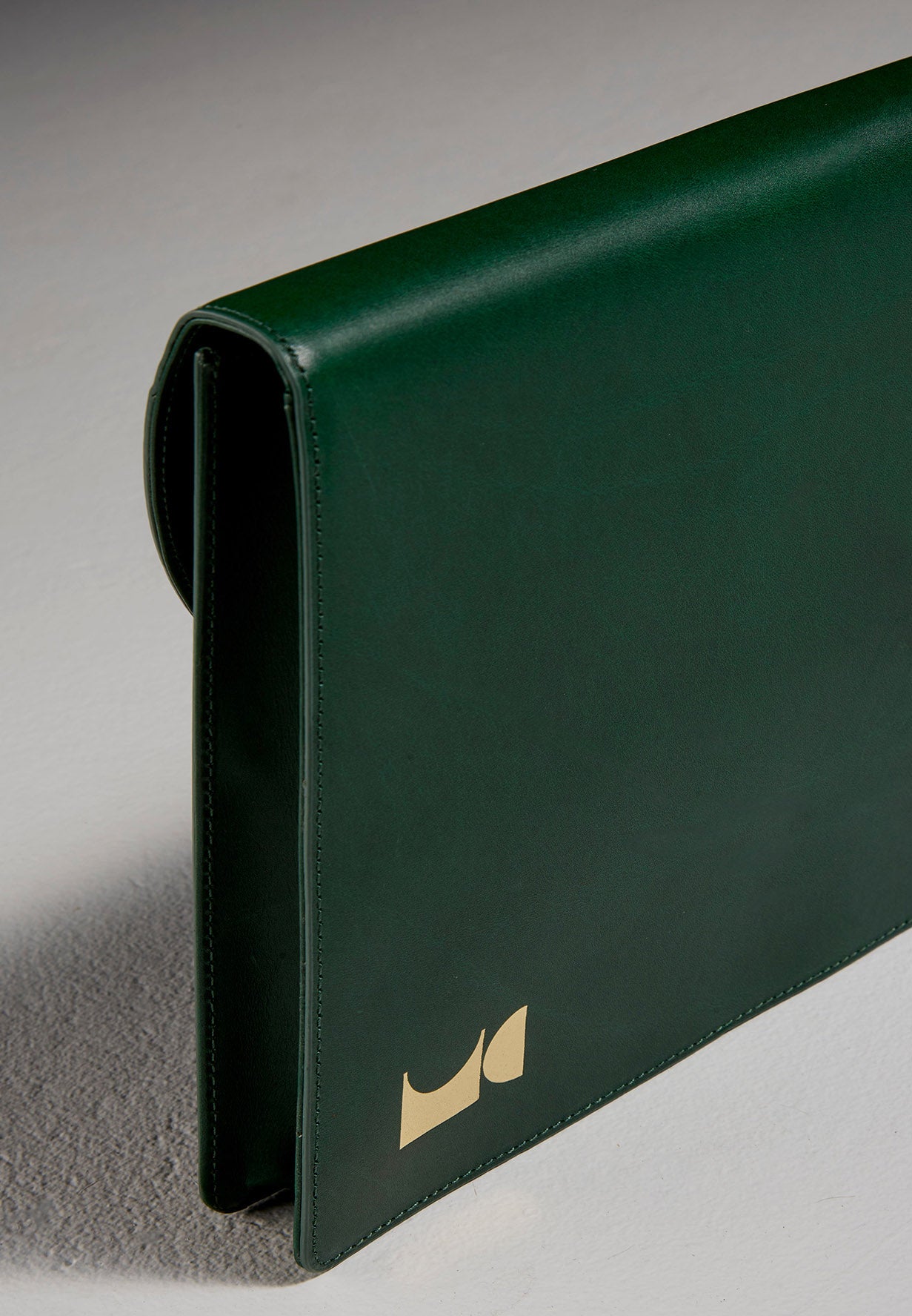 Angled view of green leather document folio sitting in front of black backdrop