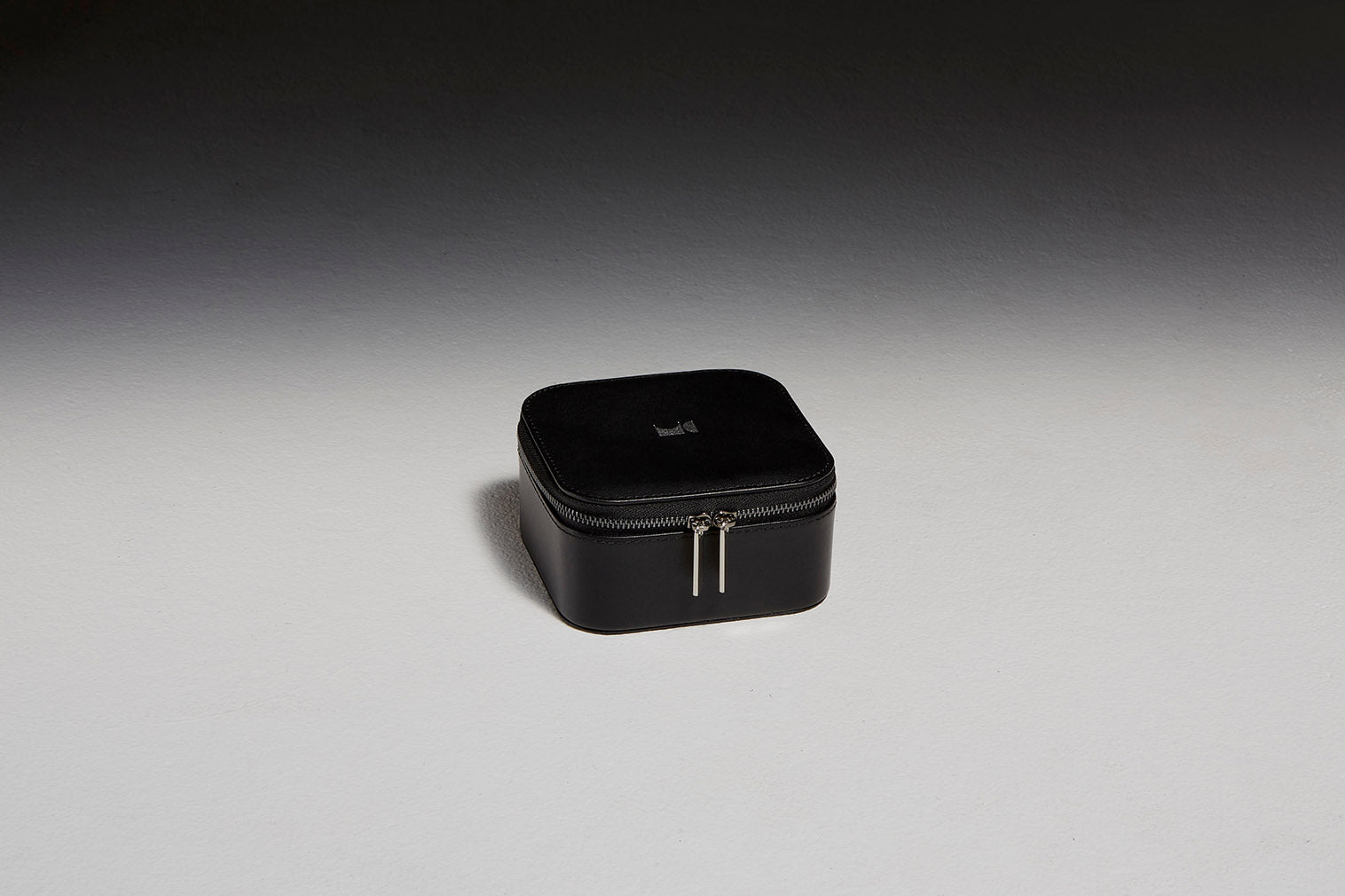 Black leather jewelry case sitting in front of a black backdrop