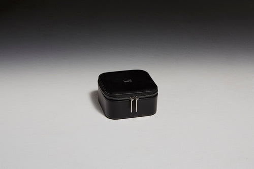 Black leather jewelry case sitting in front of a black backdrop
