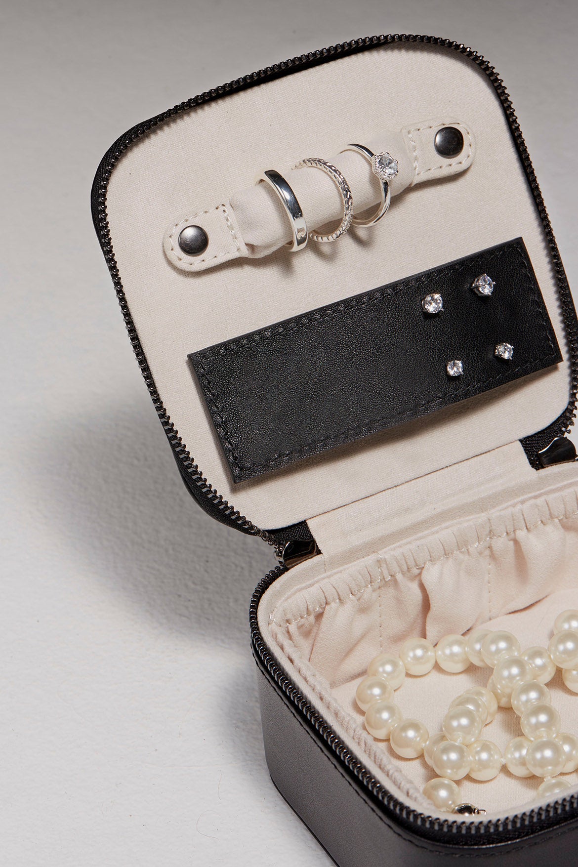 Jewelry case opened revealing rings, pearls, and earrings