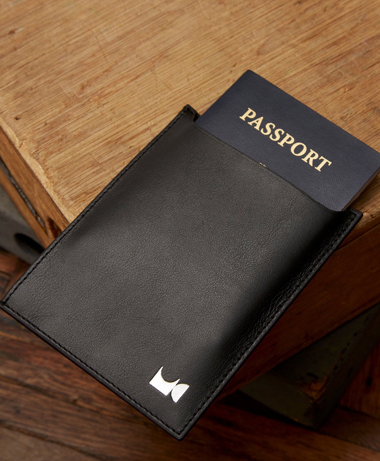 Black leather passport holder sitting in on table holding a passport