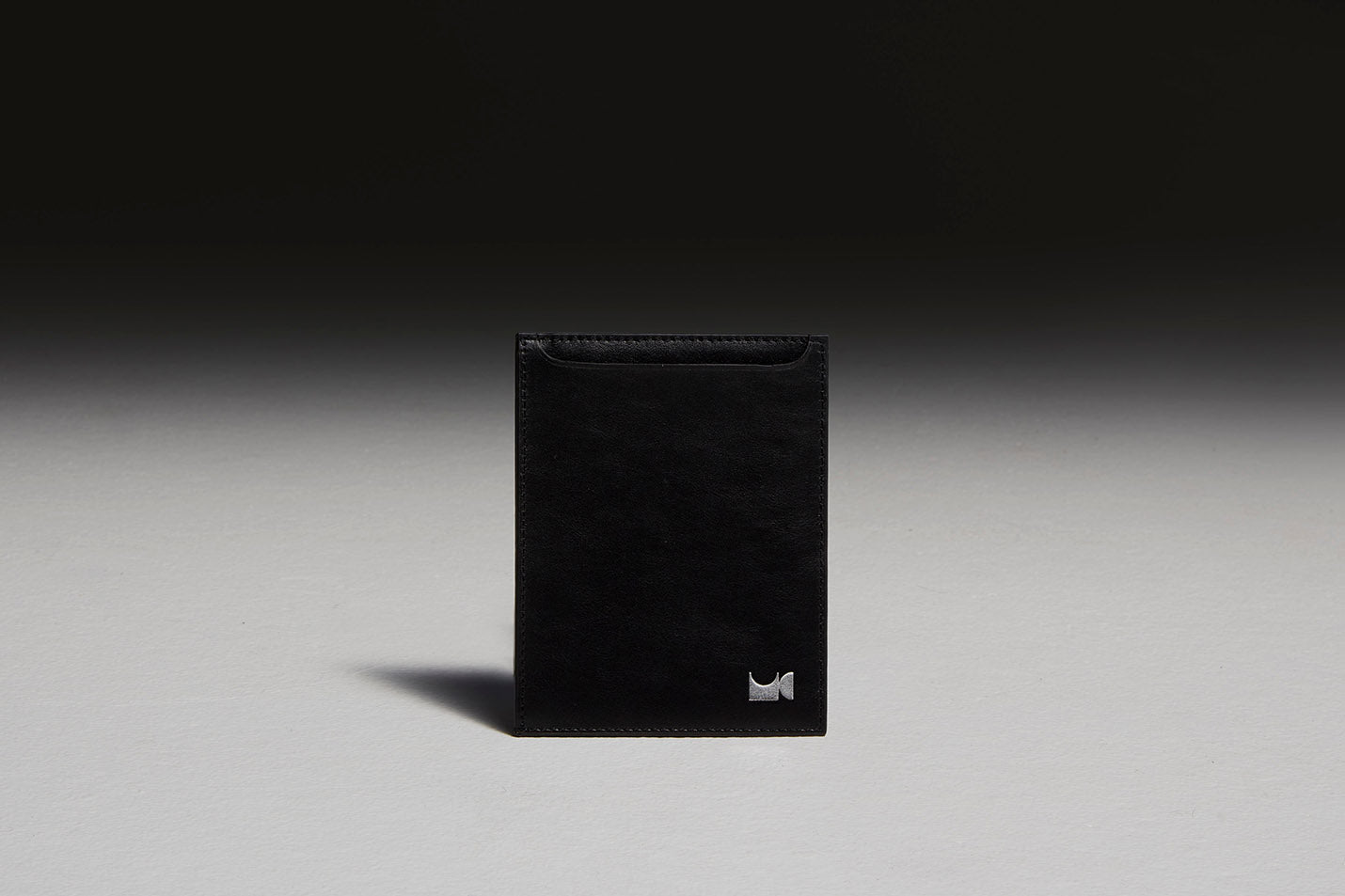 Black leather passport holder sitting in front of black backdrop