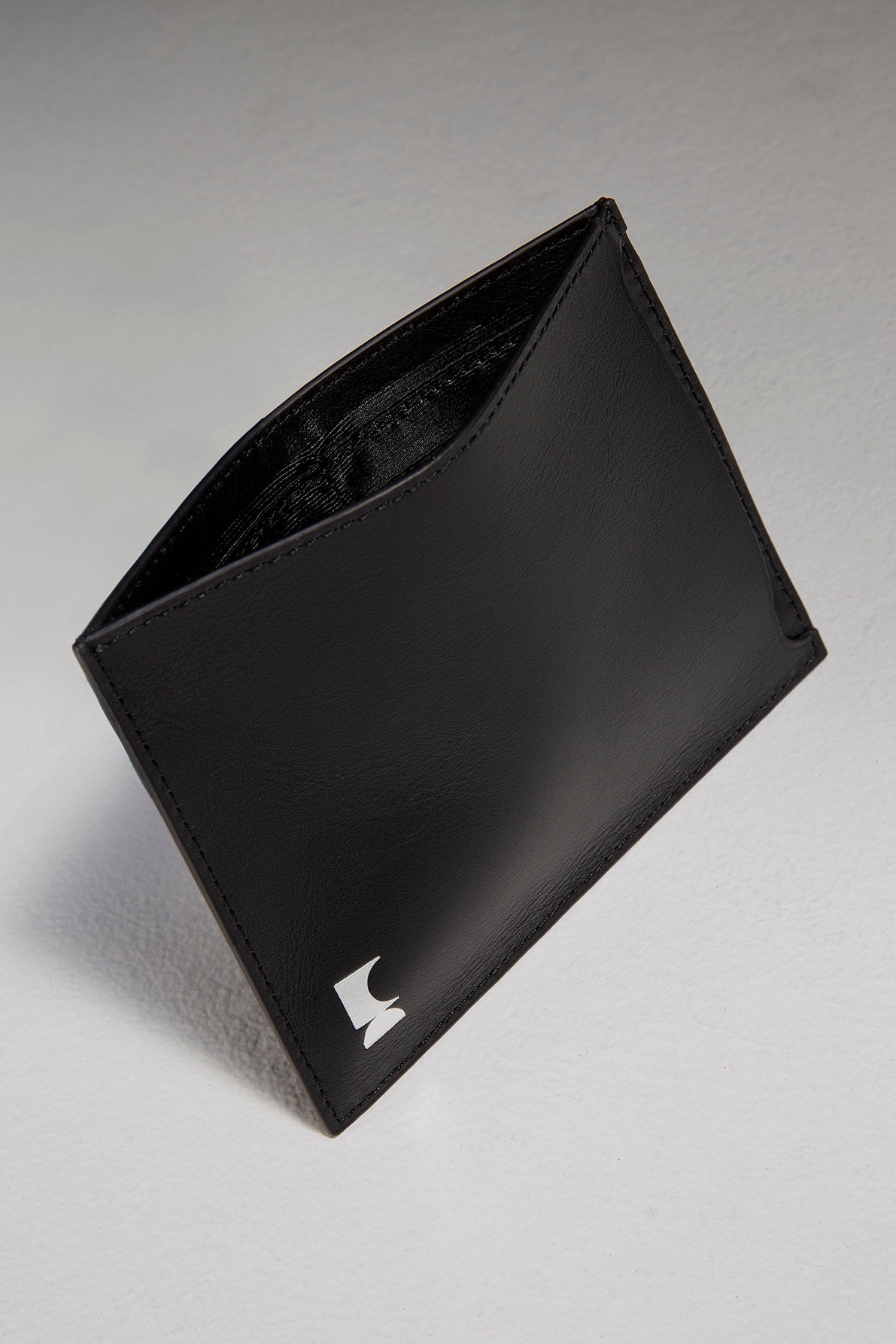 Black leather passport holder sitting in front of black backdrop with its top opened