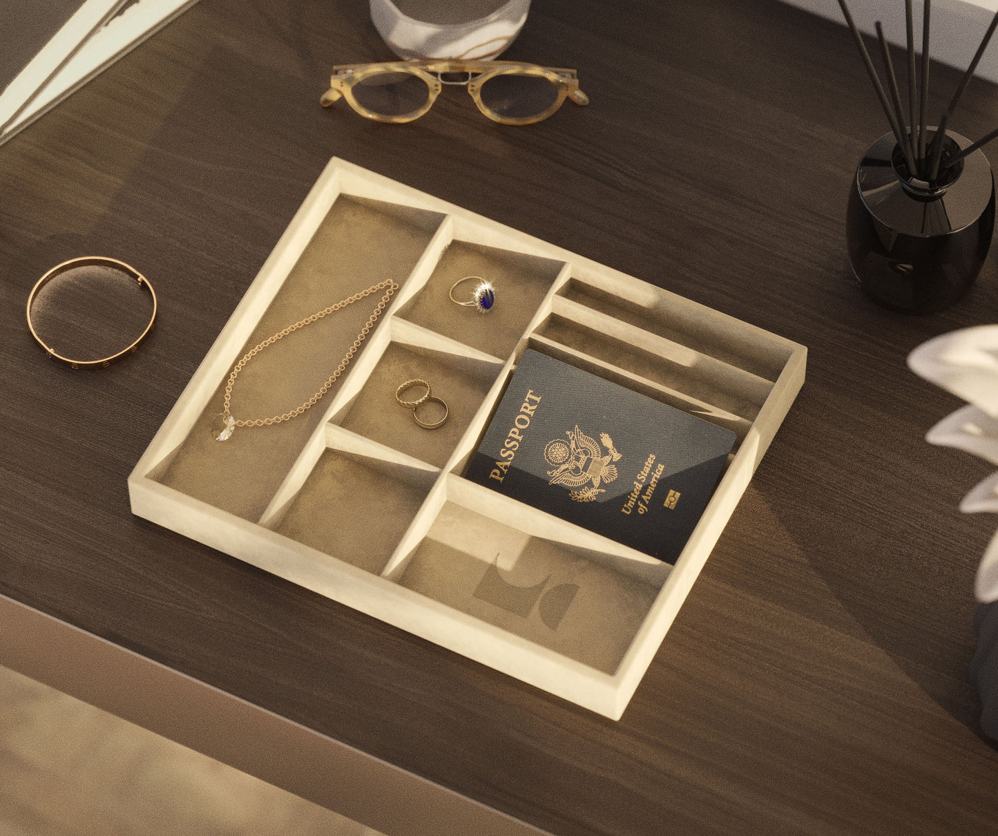 A lifestyle shot of an angled beige 7 Mix Tray containing jewelry and a passport sitting on an office desk