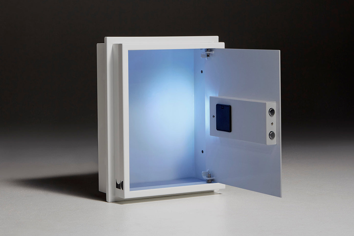 Opened white wall safe sitting in front of black backdrop. Showing interior light