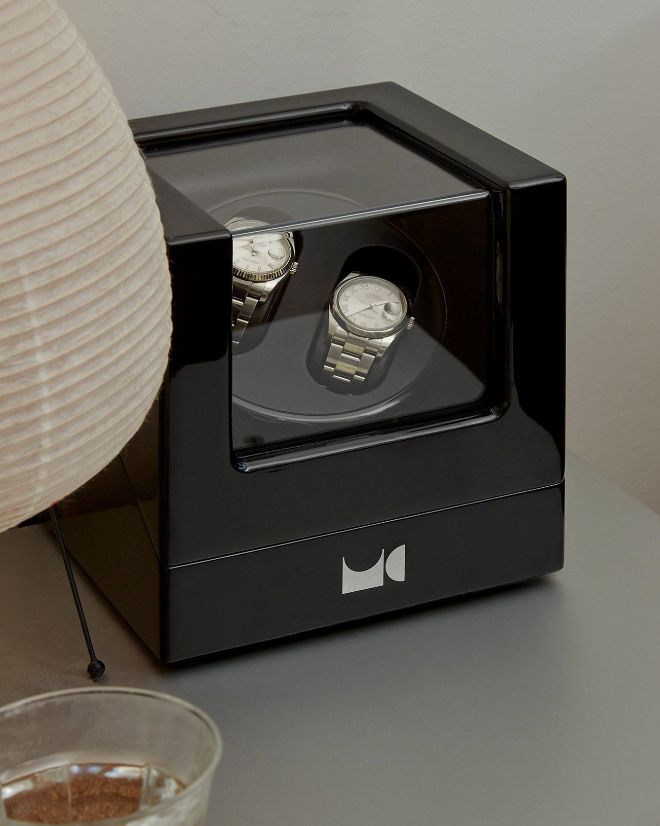 Watch winder with two watches on table.