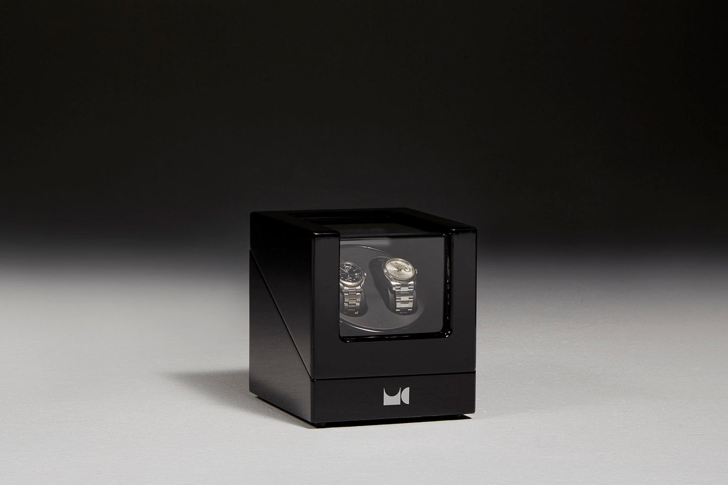 Watch winder with two watches behind black backdrop